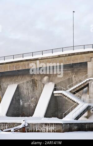 Diga in cemento con scala coperta di neve. Foto Stock