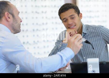 ottico che consiglia un paio di occhiali Foto Stock
