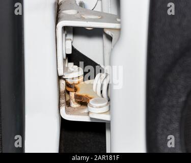 Ostruzione della cerniera della portiera usurata, cigolio e arrugginita sul carrello del raccoglitore. Concetto di manutenzione, assistenza e riparazione del veicolo Foto Stock