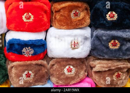 Cappellini in pelliccia con stelle rosse nel negozio di souvenir di Mosca Street. Cappelli invernali, divisa militare sovietica e russa, in viaggio verso la Russia, gi turistica Foto Stock