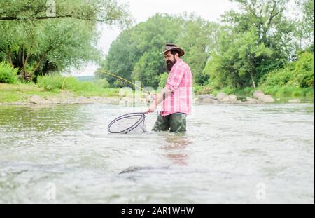 La pesca è uno sport all'aperto ricreativo accessibile con sedia a rotelle sorprendente. Hobby di pesca. Pesce alla trota pescatrice con rete. La pesca fornisce quel collegamento con il mondo vivente intero. Trova la tranquillità. Foto Stock