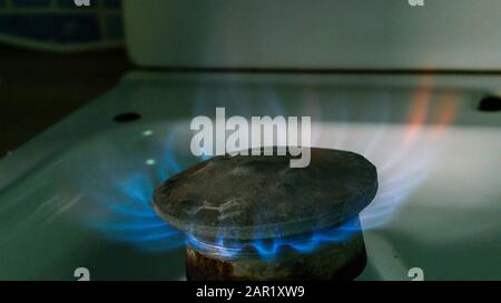 Combustione di gas naturale. Fuoco da piano di cottura vecchio bruciatore, in cucina domestica per cucinare con fiamme gas propano o metano che brucia. Primo piano. AlL'Interno. Foto Stock