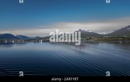 Vista incantevole di Akureyri, Islanda, sulla riva di un lago con montagne innevate sullo sfondo Foto Stock