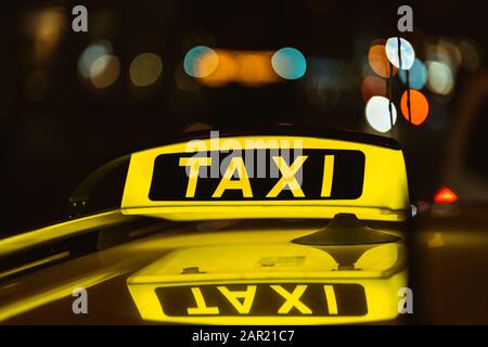 Segno nero e giallo del Taxi di notte messo sopra parte superiore di un'auto Foto Stock