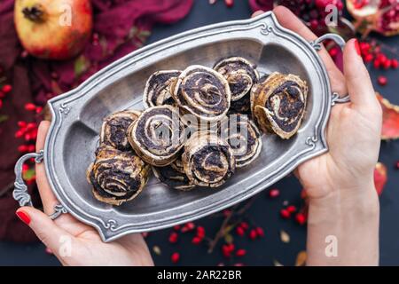 Donna che tiene i rotoli grezzi di papavero vegano su una piastra di metallo Foto Stock