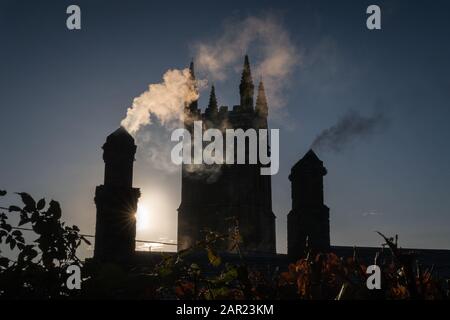 Una giornata invernale asciutta e luminosa (giorno di Natale) guardando verso la chiesa parrocchiale attraverso il fumo camino, Stoke Climsland, Cornovaglia Foto Stock