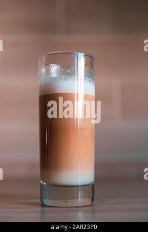 tazza di caffè multistrato in una tazza di vetro su sfondo mattone Foto Stock