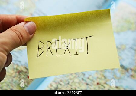 Primo piano di una persona che tiene una nota appiccicosa che dice "Brexit" su una mappa Foto Stock