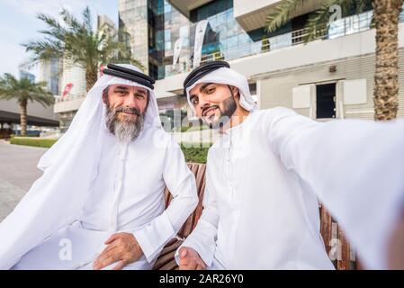Due uomini d'affari con abiti tradizionali emirates a Dubai - adulti anziani e giovani che hanno affari negli Emirati Arabi Uniti Foto Stock