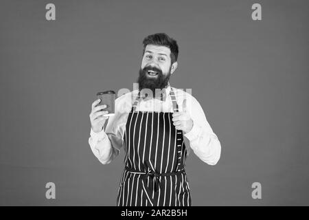 Miglior gusto mai. elegante fiducioso barista maschio bere il caffè. uomo barbuto tenere take away caffè. brutale cameriere cafe. uomo maturo sfondo rosso. Esperti servo. barista hipster chef grembiule. Foto Stock