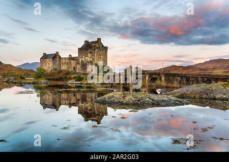 Alba sopra Eilean Donan castello riflesso nelle acque ancora del lago a Dornie nelle Highlands della Scozia Foto Stock