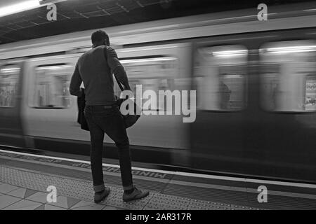 Un uomo aspetta che il treno della metropolitana si fermerà alla stazione della metropolitana di Canary Wharf a Londra, Regno Unito Foto Stock