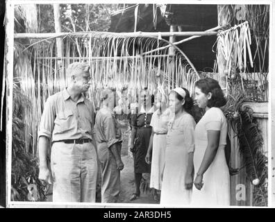 [Due uomini bianchi in uniforme tropicale che parlano a quattro donne indonesiane in un villaggio decorato] Data: 1940-1945 luogo: Indonesia, Indie orientali olandesi Parole Chiave: Popolazione, uomini, seconda guerra mondiale, donne Foto Stock