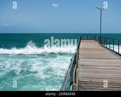 Mare mosso che smashing sulla barriera corallina e il molo di Port Noarlunga in Australia del sud il 23rd gennaio 2020 Foto Stock