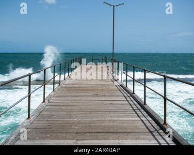 Mare mosso che smashing sulla barriera corallina e il molo di Port Noarlunga in Australia del sud il 23rd gennaio 2020 Foto Stock