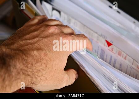 Un uomo caucasico che guarda all'interno di un armadio di deposito per i registri fiscali. Foto Stock