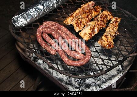 Un'ottima dose di carne cucinata un barbecue su un portico di legno Foto Stock