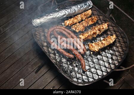 Un'ottima dose di carne cucinata un barbecue su un portico di legno Foto Stock