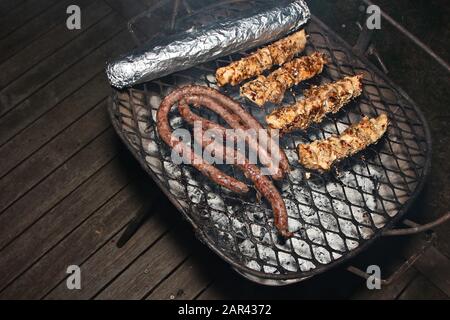 Un'ottima dose di carne cucinata un barbecue su un portico di legno Foto Stock