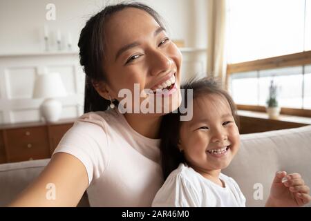 Immagine autoritratto di mamma asiatica sorridente e figlia piccola Foto Stock