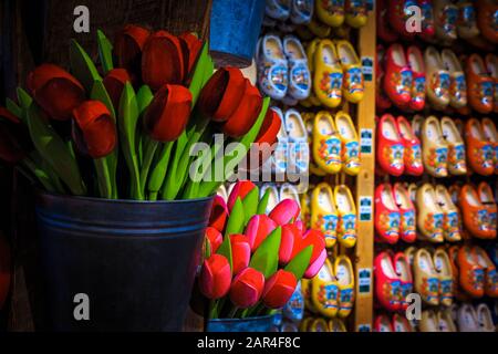 Splendidi bouquet colorati di tulipani di legno nel secchio e scarpe di legno in fila sulla parete. Negozio di souvenir olandese con oggetti di artigianato Foto Stock