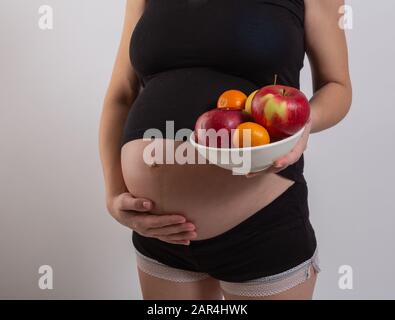 Gravidanza e sana alimentazione biologica. La donna incinta conserva frutta fresca di vitamina, spazio libero. Inserire il testo. Concetto di aspettativa e di salute. Foto Stock