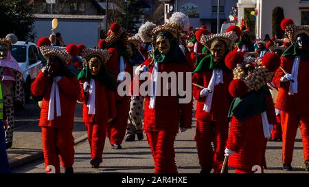 Elzach, Germania, 25 febbraio 2017, Molte persone camminano lungo la strada con tradizionali costumi rossi e maschere che celebrano il carnevale nella foresta nera Vil Foto Stock