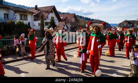 Elzach, Germania, 25 febbraio 2017, Gruppo di persone con maschera di carnevale tradizionale e cosumes in villaggio di foresta nera a piedi con processione lungo t Foto Stock