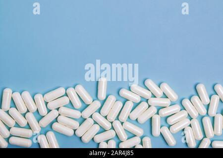 Pillole mediche bianche su sfondo blu con spazio di copia. Foto Stock