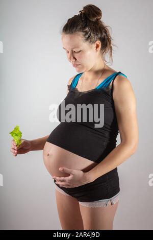 Donna incinta che tiene insalata fresca in studio Foto Stock