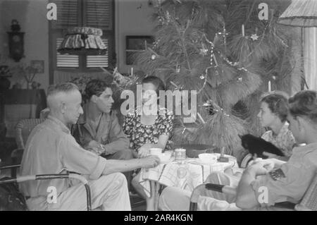 Fiori per la celebrazione dei morti e di Natale a Semarang un'azienda intorno ad un tavolo vicino ad un albero di Natale decorato Data: 25 dicembre 1947 luogo: Indonesia, Indie orientali olandesi Foto Stock