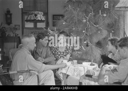 Fiori per la celebrazione dei morti e di Natale a Semarang un'azienda intorno ad un tavolo vicino ad un albero di Natale decorato Data: 25 dicembre 1947 luogo: Indonesia, Indie orientali olandesi Foto Stock