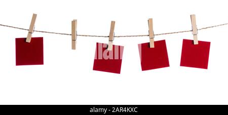 Set di quattro rosso vuoto note di carta tenuto su una stringa con clothespins isolati su sfondo bianco Foto Stock