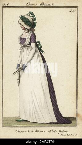 Donna alla moda nel cappello Minerva ai Giardini di Tivoli, 1798. Indossa un cappello in stile Minerva, chiamato per la sua somiglianza con il casco della dea romana della saggezza. Il cappello è decorato con una corona di fogliame e nastri. Indossa un grembiule bianco su un abito a righe. 23 Giugno 1798. Jardin de Tivoli. Chapeau a la minerve, abito zebree. 24 Prairial An 6. Incisione su copperplate colorata a mano di Journal des Modes et Dames di Pierre de la Mesangere, Parigi, 1798. Le illustrazioni del volume 1 erano di Carle Vernet, Claude Louis Desrais e Philibert Louis Debugcourt. Foto Stock
