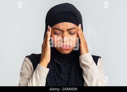 Ragazza Musulmana Afro Ammalata Nei Templi Toccanti Di Hijab, Che Soffre Di Mal Di Testa Foto Stock