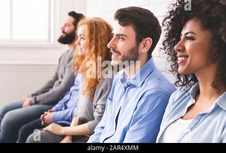 Persone millennarie multietniche sedute di fila e che guardano al relatore Foto Stock