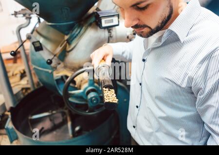 Barista che torreda il caffè con una macchina Foto Stock