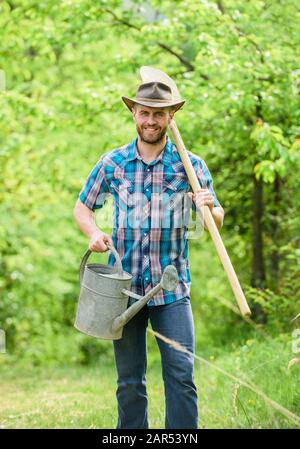 La coltivazione di piante. Coppia guy cappello da cowboy con annaffiatoio e pala. Arbor Day. La piantagione di alberi. Impegno e responsabilità. Concetto di agricoltura. La semina in giardino. La piantumazione di alberi di tradizione. Foto Stock