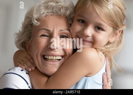 Adorabile amorevole bambina piccola abbracciando felice nonna anziana, ritratto. Foto Stock