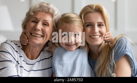 Bambina che abbraccia la giovane madre e sorride la nonna di mezza età. Foto Stock