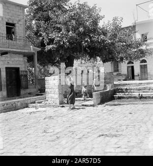 Israele - Peki'nel villaggio di Peki'in Galilea. Una strada freelance alla fonte locale. Ragazzi e uomini hanno guardato l'ombra di un albero. Le donne sono impegnate in pozzi d'acqua Data: 1 gennaio 1963 Località: Israele, Peki'in Parole Chiave: Alberi, villaggi, bambini, pareti, immagini di strada, fonti d'acqua Foto Stock