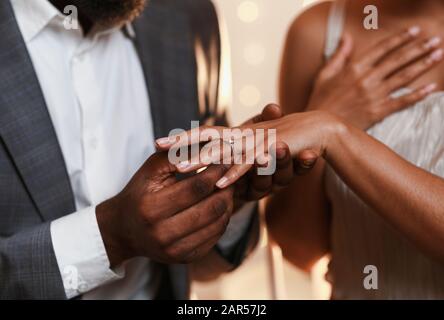 Primo piano di afro uomo che mette l'anello sul dito della donna Foto Stock