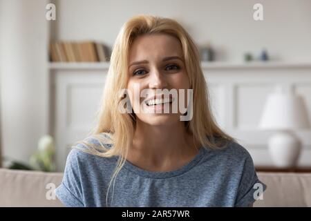 Piacevole ragazza che guarda la macchina fotografica, tenendo la videochiamata con i genitori. Foto Stock