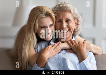 Attraente giovane donna bionda sorridente che abbraccia una mummia piacevole più vecchia. Foto Stock