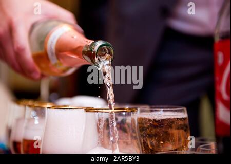 Lo champagne di una bottiglia viene versato in un calice di vetro. Primo piano Foto Stock