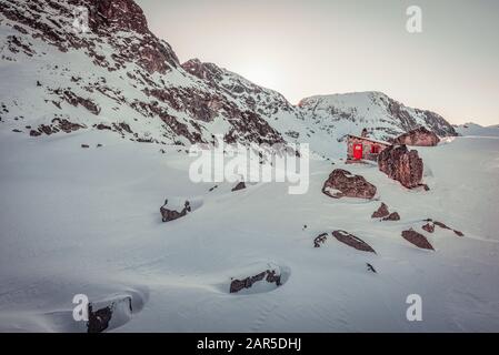 Ghiaccio e neve coperta piccola capanna di riparo di pietra, in piedi sulla cima della vetta in inverno Foto Stock