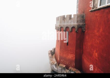 Vista di dettaglio di una colonna a cupola rossa al Palazzo pena (Palacio da pena) completamente inghiottita nella nebbia con vista scarsa della vicina foresta Foto Stock
