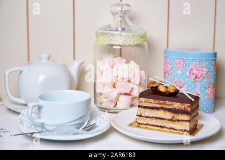 Una fetta di torta con noci e una teiera con una tazza sul tavolo. Foto Stock