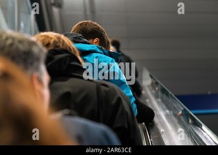 Persone anonime che si muovono su scale mobili, vista da dietro, dettaglio sulla loro testa - concetto di trasporto Foto Stock