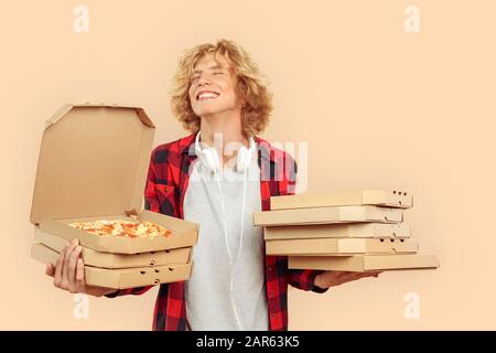 Giovane uomo che tiene scatole di cartone pizza in mani e gioito Foto Stock